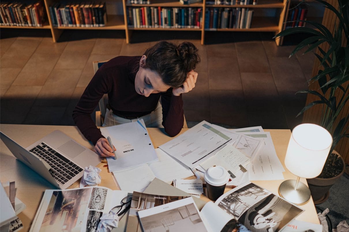 A woman sitting at a desk, working on papers and using a laptop for her tasks.